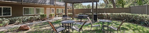 a patio with tables and chairs in front of a house