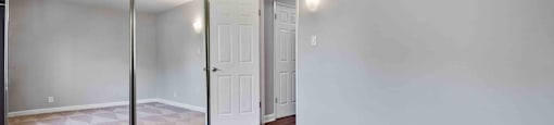 an empty living room with mirrored walls and a door to a closet