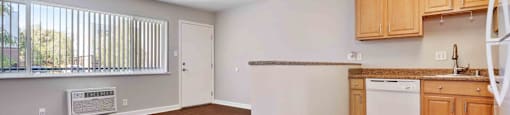 an empty living room and kitchen with wood flooring and a window