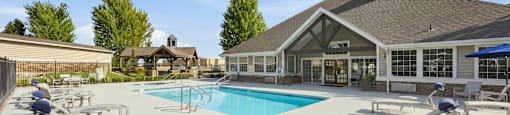 A pool area with sun loungers and a building in the background.