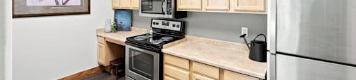 A kitchen with wooden cabinets and a stainless steel refrigerator.