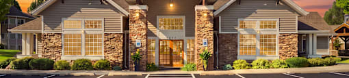 A parking lot in front of a building with a stone facade and a large entrance.