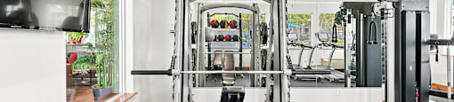 A gym with a variety of equipment including a squat rack, bench, and weights.