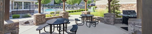 A wooden pavilion with tables and chairs is set up outside.