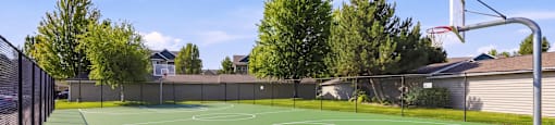 A basketball court with a green surface and a basketball hoop on the right side.