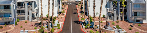 Three-Bedroom Apartments in North Mountain Village, Phoenix, AZ - Ardella on 28th - Property Exterior with Private Balconies, Palm Trees, Street View, and Mountains in the Background
