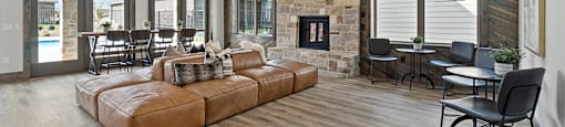 Homes in San Antonio, TX for Rent - Winding Brook - Clubhouse with Wood-Style Flooring, Leather Sofas, Tables and Chairs, Floor-to-Ceiling Windows, Stone Mantel, Fireplace, Cathedral Ceiling, and Ceiling Fan.