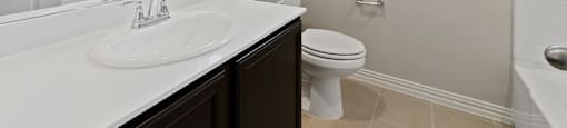 Apartments in Lewisville, TX - The Villas at Rockbrook - Bathroom with a Large Mirror and Granite Countertop.