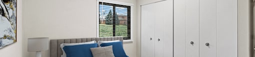 A bedroom with a large bed and a window with blinds.