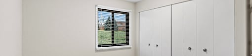A room with a window, carpeted floor, and a wall-mounted cabinet.