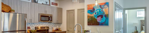 Apartments for Rent in Georgetown, Texas - Williamson at the Overlook - Kitchen with Sandy Granite Counters, Stainless Steel Appliances, TIle Backsplash, Light Cabinetry, and Cooking Island with Seating and Hanging Lights