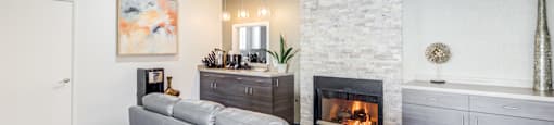 A grey couch sits in front of a fireplace in a modern living room.