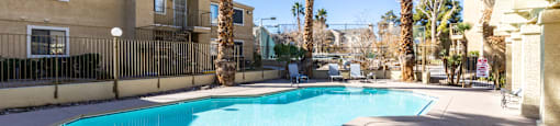 A swimming pool surrounded by palm trees and apartment buildings.
