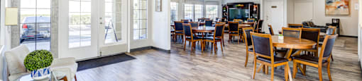 A large open space with a dining area and a kitchen in the background.