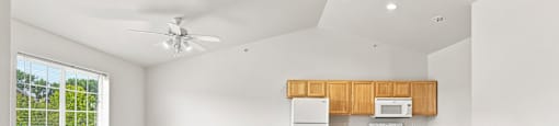 A spacious kitchen with a ceiling fan and a window with blinds.