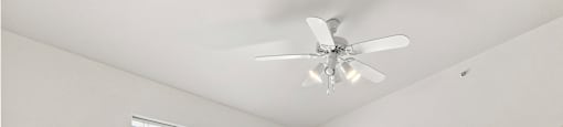 A room with a ceiling fan and a window with blinds.