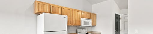 A kitchen with a white refrigerator, stove, and microwave.