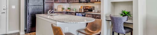 a kitchen with a bar and chairs and a refrigerator at LIV at Boerne Hills an Active Senior Community 62+, Boerne