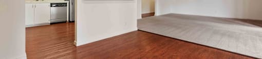 an empty living room and kitchen with wood floors and a ceiling fan