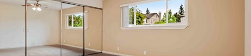 Apartments for Rent in Fremont - Logan Park - Large Empty Bedroom with Mirrored Closet, Ceiling Fan, Carpet, and Window
