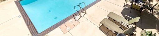 Apartments for Rent in Fremont, CA - Northgate Savoy - Swimming Pool with Lounge Seats, Tables, Chairs, Umbrellas, and Tropical Trees.