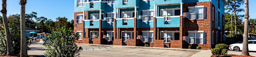 A multi-story building with a parking lot in front.