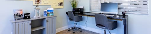 A room with a desk, chairs, and pictures of house floor plans.