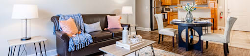 A living room with a couch, chairs, and a dining table.