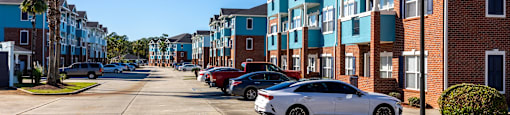 A street view of a residential area with cars parked on the side.