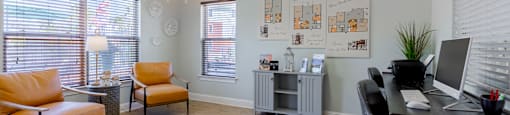 A room with a black desk and orange chairs.