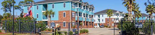 A large building with a blue and red facade is surrounded by a black fence.
