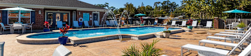 A pool area with sun loungers and a blue umbrella.