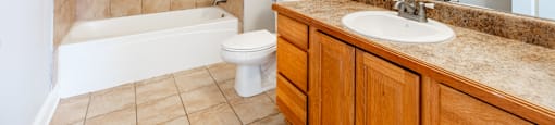 A bathroom with a beige tile shower and a white toilet.