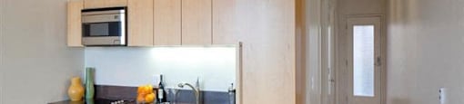 Portland, OR, Pet-Friendly Apartments - The Beverly - Kitchen with Hardwood Floor, Wooden Cabinets, Stainless-Steel Appliances, and Living Stone Countertop.