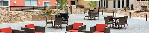 San Rafael, CA, Pet-Friendly Apartments - Rafael Town Center - Fire Pit Lounge Area With Lounge Seats, Tables, Chairs, And Umbrellas.
