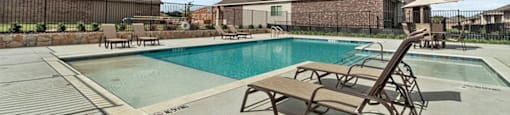 Homes in Lewisville, TX for Rent - The Villas at Rockbrook - Swimming Pool with Spacious Sundeck, Lounge Seats, Umbrella Tables, and Chairs.