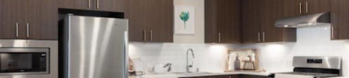 2-Bedroom Apartments in Santa Clara, CA - Santana Terrace - Kitchen with Stainless Steel Appliances, Dark Brown Cabinetry, and Modern Hardware