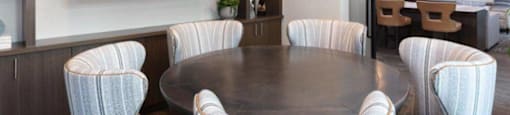 Apartments for Rent in Santa Clara, CA - Santana Terrace - A Dining Area with a Round Table, Upholstered Chairs, and a Large Wall-Mounted TV.