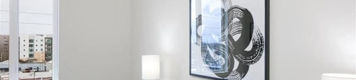 Pet-Friendly Apartments in Beaverton, OR - Westline - Bedroom with Vinyl Hardwood Flooring, Bed, Nightstands with Lamps, Wall Art, and Spacious Window.