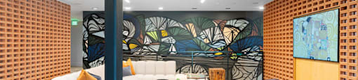 A modern seating with a large mural on the wall, couches, and a tv inside The Laura community lounge.