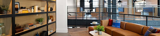 A modern seating area inside The Laura office with a long wooden shelf on the left side and a brown sofa in the center.