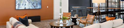 A resident lounge with a large couch, a coffee table, and a painting on the wall.