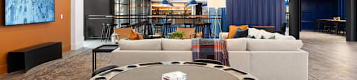 A modern resident lounge with a round poker table and chairs.