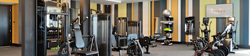 A gym with a variety of equipment including treadmills, weights, and exercise machines.