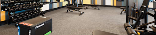 A gym with a variety of equipment including dumbbells, weight machines, and a bench.