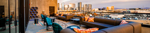 A rooftop patio with a view of the city skyline at dusk.