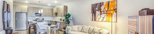 a living area with a couch coffee table and chair and a kitchen in the background