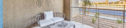 a patio with a white couch and coffee table and a large window with a view of a