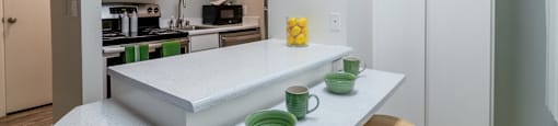 Hayward, CA Apartments Near Hayward BART Station - Paseo Gardens - Kitchen with White Cabinetry, Stainless Steel Appliances, Granite Countertops, Large Pantry Doors, Large Island with Seating and Breakfast Bar Section, and Tile Flooring