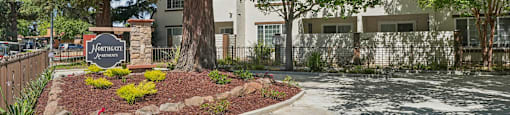 a sidewalk in front of a building with trees and a sign